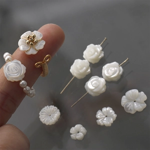 Detailed macro view of white shell-carved rose and five-leaf flower charms for DIY jewelry