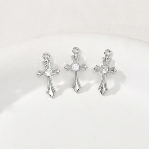Three silver cross pendants with central zircon and pavé detailing on a ceramic dish