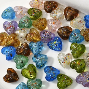 Dettaglio macro di perle di vetro a forma di cuore da 15 mm con particelle di lamina colorata