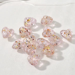 Dettaglio di perline a cuore rosa traslucide con scaglie colorate per gioielli fai da te