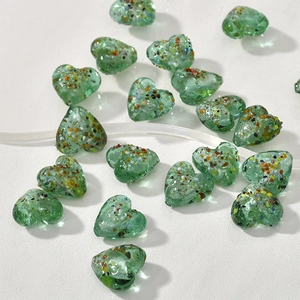 Dettaglio di perline di vetro a cuore verde da 15 mm con macchie colorate per gioielli