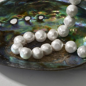 Close-up of iridescent baroque pearl beads displayed inside a glossy abalone shell