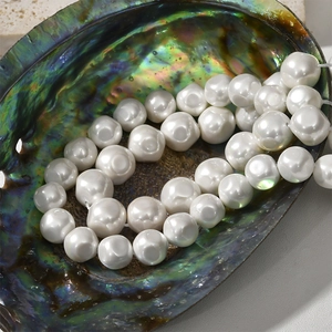 Close-up of white baroque shell pearls in a colorful iridescent abalone shell bowl