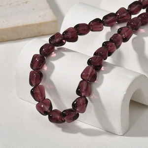Macro shot of irregular deep purple glass beads for jewelry making on a white stone background