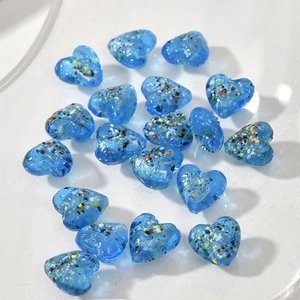 Dettaglio macro di perle di vetro blu a forma di cuore con particelle colorate