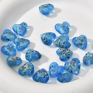 Vista macro di perle a cuore in vetro blu scuro da 15mm con scaglie glitterate colorate