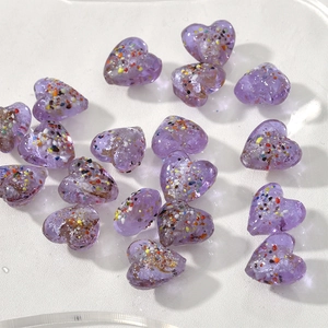 Dettaglio macro di perline a cuore viola 15mm con glitter per creazione di gioielli DIY