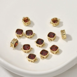 Detailed close-up of 14k gold plated square charms with red cubic zirconia and side hollow patterns