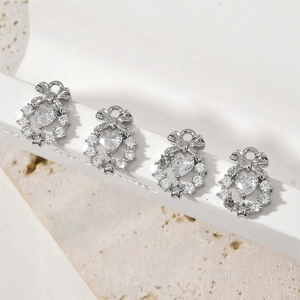 Dettaglio di quattro ciondoli a fiocco e cuore in zirconia per la creazione di gioielli fai da te