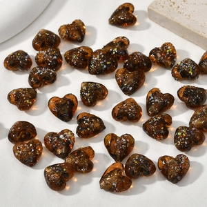 Dettaglio macro di perle a cuore in vetro ambrato da 15 mm con scaglie colorate per DIY