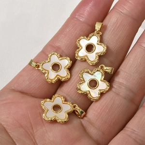 Macro view of 18k gold-plated flower charms with white shell inlay for DIY jewelry making