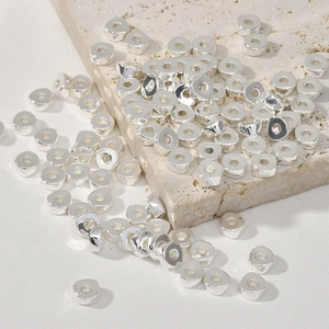 Gros plan de perles d'espacement rondes argentées pour création de bijoux sur pierre