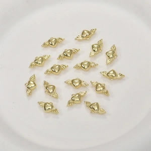 Mini vergoldete Herz-Flügel-Anhänger für DIY-Schmuck auf einem weißen Tablett präsentiert