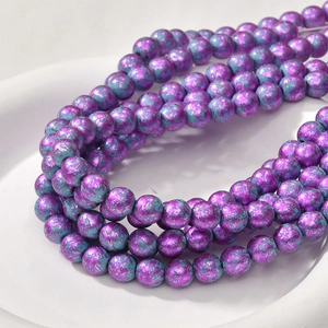Macro shot of 8mm purple and cyan oil painting style turquoise beads on white tray