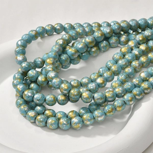 Detailed view of 8mm turquoise oil painting style beads with gold and silver splash effects