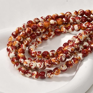 Macro detail of 8mm marble textured round beads with vibrant red and orange swirls