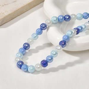 Blue and iridescent 8mm glass beads arranged on a white ceramic plate for DIY jewelry