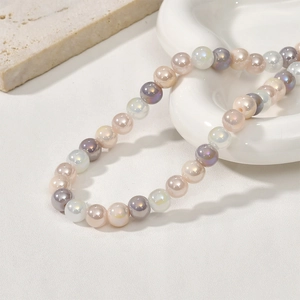 Macro shot of 8mm colorful glass beads necklace on a ceramic tray with pearl luster