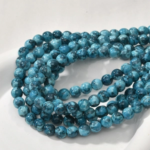 Macro view of 8mm colorful oil painting style round turquoise beads in a ceramic tray