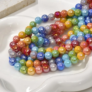 Close-up of 8mm colorful pearlescent glass beads on a white decorative ceramic tray