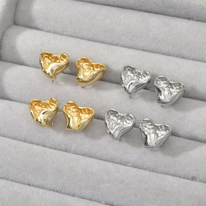 Lava textured heart-shaped earring studs in gold and silver finish on jewelry tray