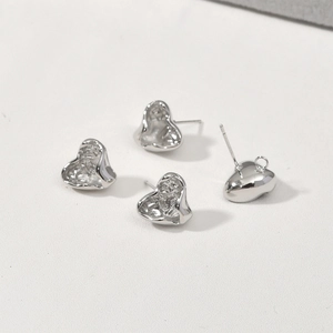 Detailed view of silver heart earrings with lava texture and secure pin closure