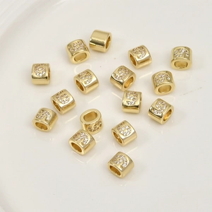 Detailed view of 14k gold plated cylindrical beads with number 9 cubic zirconia inlay