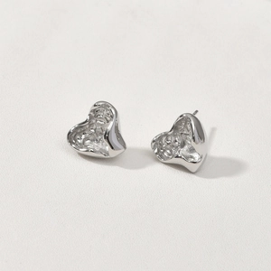 Macro detail of silver-tone 14k gold plated heart studs with unique lava texture effect