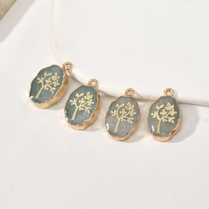 Detail van vier ovale kristallen hangers met gouden levensboommotoef voor DIY-sieraden