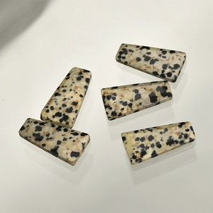 Detailed view of flat trapezoid Dalmatian stone pendants with natural spotted textures