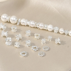 Silver flower spacer beads for DIY jewelry making on luxury champagne silk background