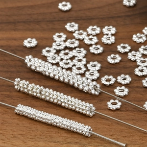 Thick silver-plated snowflake spacer beads for DIY jewelry making on wooden background