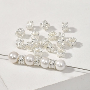 Macro detail of silver plated floral hollow spacers threaded with elegant white pearls