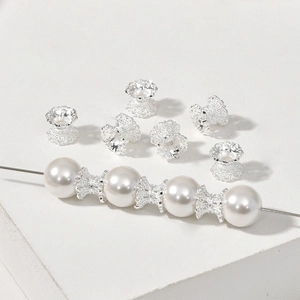 Close-up of silver-plated flower bead caps on a white pearl string for DIY jewelry making