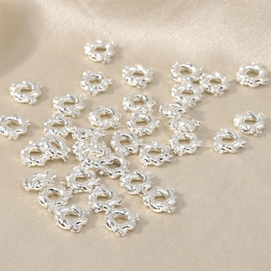 Macro shot of silver-plated flower spacer beads with twisted rope edges and white zircons