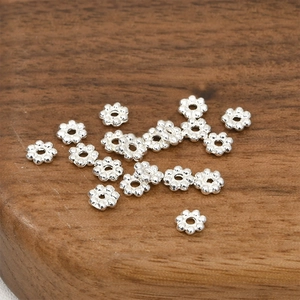 Close-up of silver flower spacer beads on wooden base for DIY jewelry making
