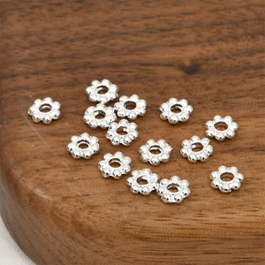 Detailed close-up of snowflake-shaped thick silver-plated spacer beads on dark wood