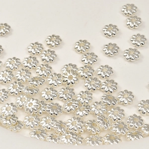 Close-up of flower-shaped spacer beads in polished silver plating for DIY jewelry