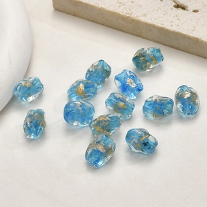 Makroaufnahme blauer unregelmäßiger Glasperlen mit Goldfolie für DIY-Schmuckherstellung