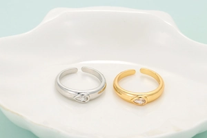 Minimalist open rings in gold and silver finish with teardrop zircon on a white plate