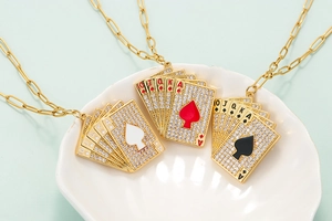 Dettaglio della collana dorata con ciondoli a forma di carte da gioco e zirconi