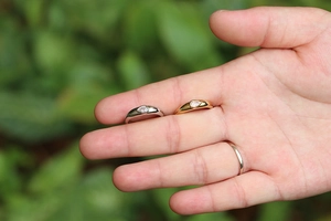 Detailed view of silver and gold rings with pear-cut cubic zirconia on a wide band