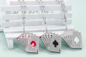Dettaglio di tre collane con ciondoli a carte da gioco e zirconi su una panchina