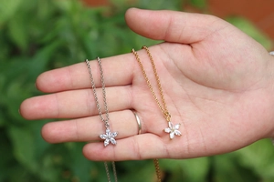 Detailed view of five-petal flower pendant necklaces with zircon inlay in gold and silver