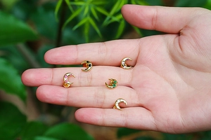Detailed view of crescent moon stud earrings with colorful zircons held in hand