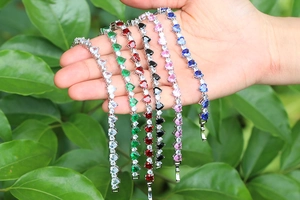 Dettaglio di braccialetti con zirconi a forma di cuore in vari colori su foglie verdi