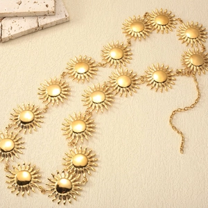 Détail d'une ceinture chaîne dorée avec breloques soleil polies et fermoir mousqueton