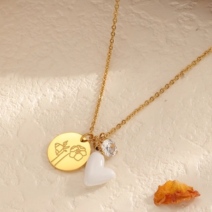 Goldene Edelstahl-Herzkette mit geblümter Scheibe und Zirkonia-Anhängern auf Steingrund