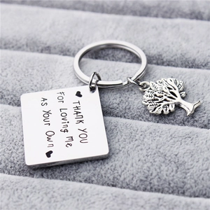 Macro detail of engraved stainless steel keychain with Tree of Life charm and heartfelt quote