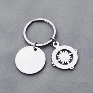 Vue macro d'un porte-clés boussole en acier inoxydable avec disque gravé sur tissu